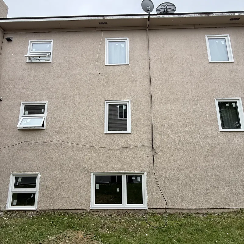 Three-storey apartment building with new windows, two of them open awning windows