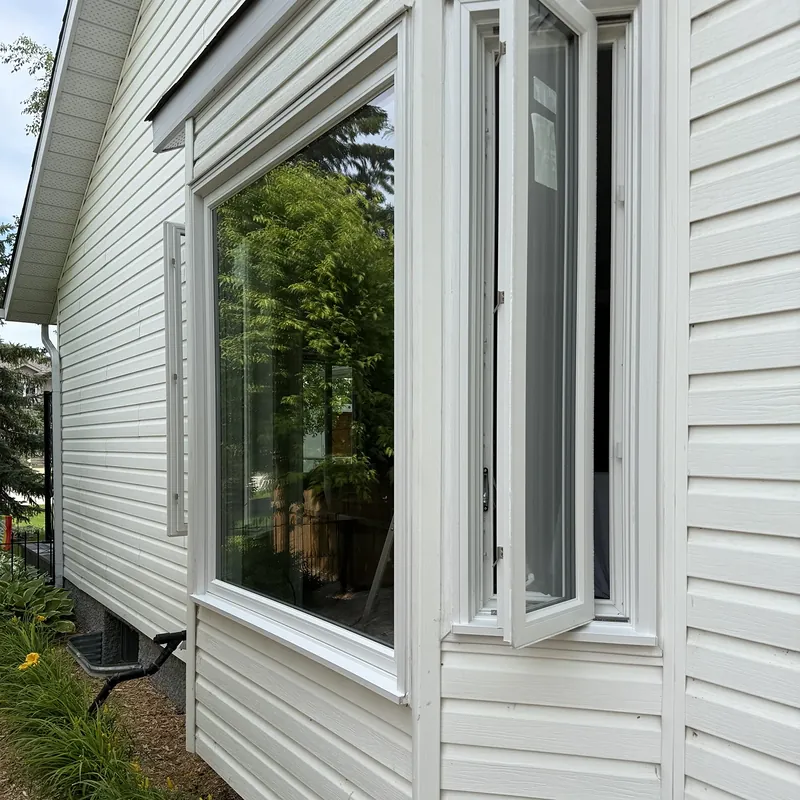Bay window on white siding, with one casement swung open