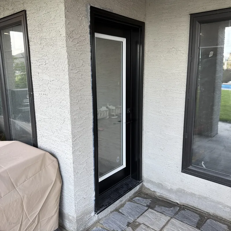 Black door with a tall glass insert between black-framed windows