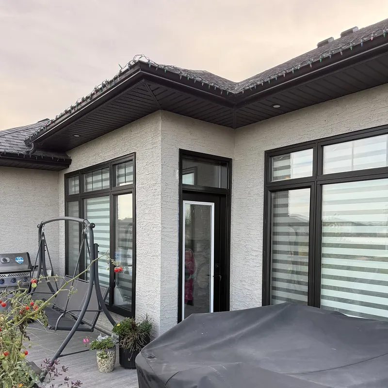 Modern stucco home with black-framed windows and doors, seen from the back deck