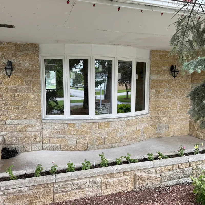 Curved bow window on a stone porch, with a planter in front