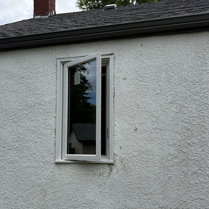 Casement window swung open on a white stucco wall