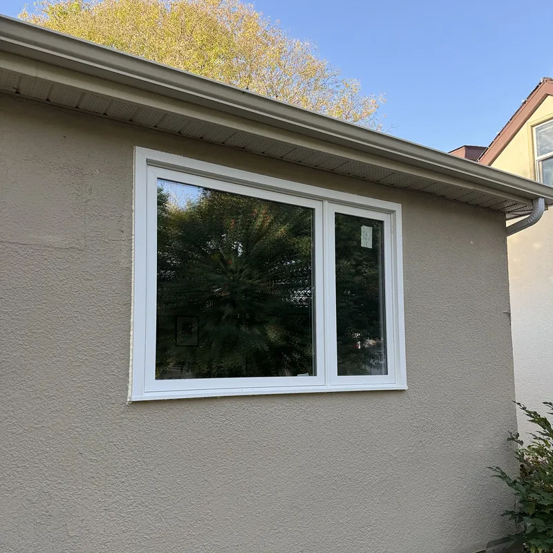 Picture window with a casement beside it on a beige stucco wall