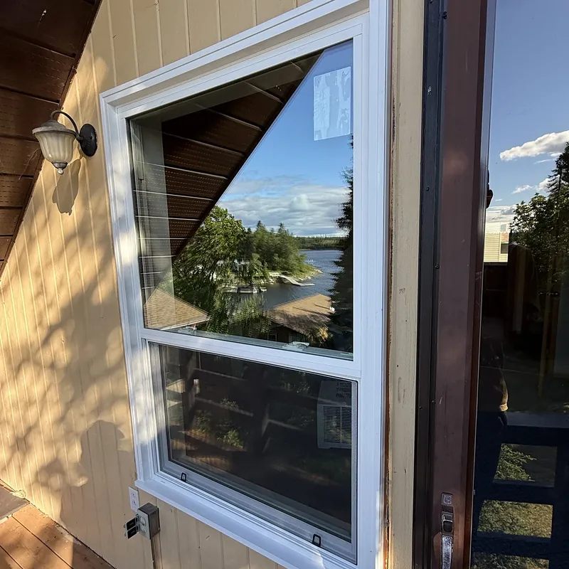 Picture window over an awning window on a lake cottage, reflecting the lake
