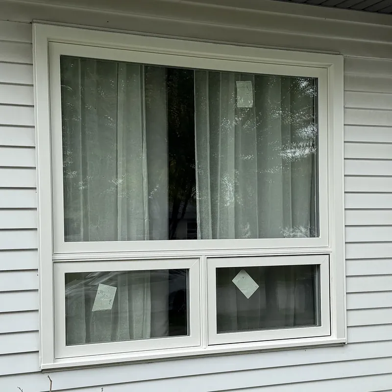 Picture window above two awning windows on white siding