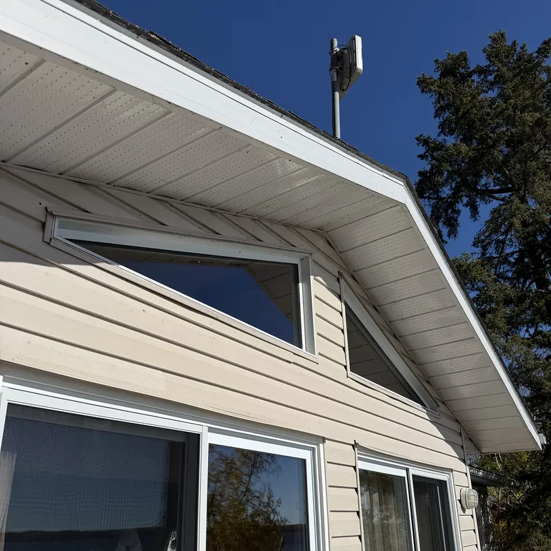Shaped gable windows above sliding doors on a cottage, under a deep blue sky