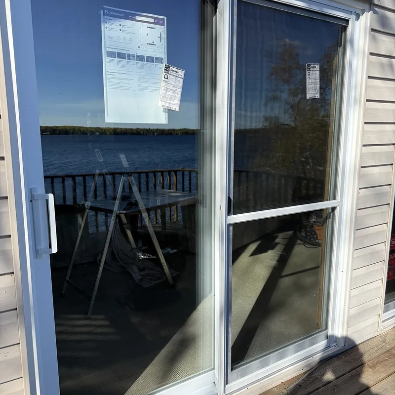 Sliding patio door reflecting the lake, with its energy labels still on