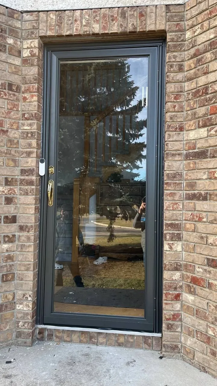 Black full-view storm door installed in a brick entry