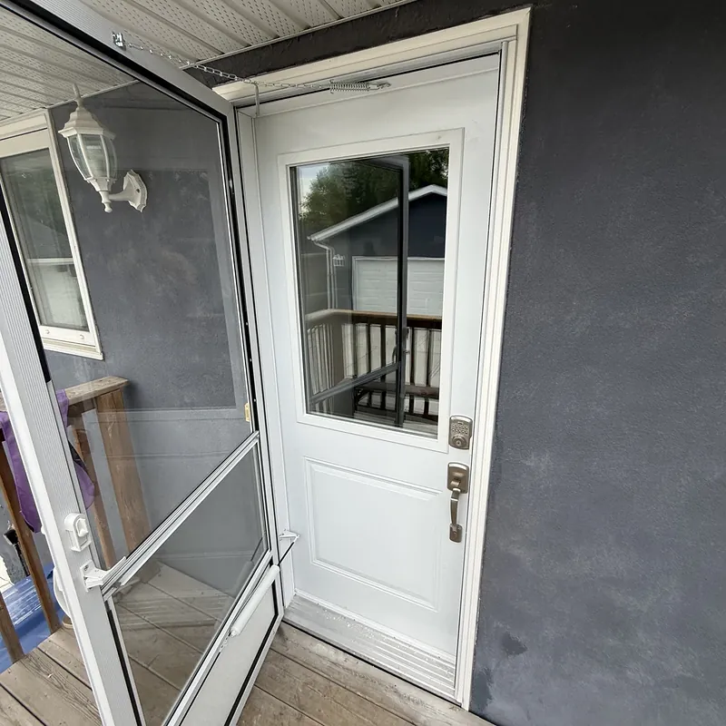 Storm door swung open in front of a white half-glass entry door