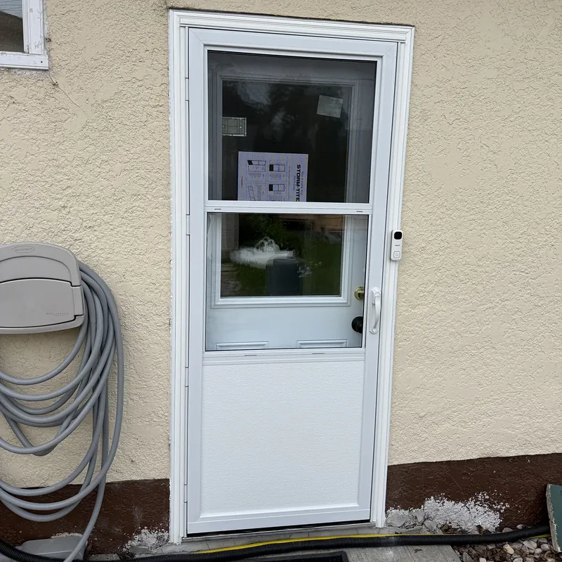 White storm door with a glass top half on a stucco wall