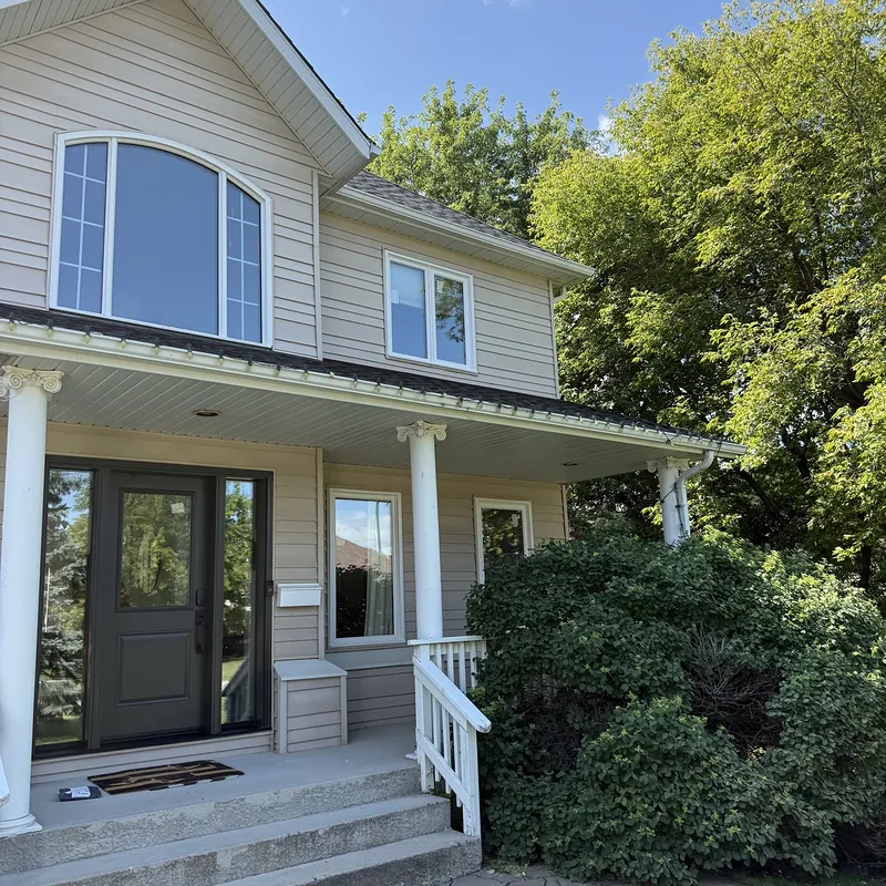 Two-storey home with a new arched window and a black front door with sidelites